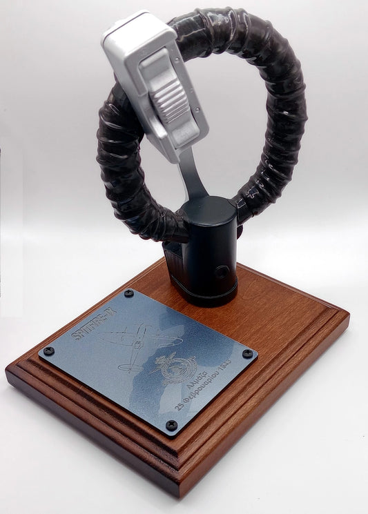 Decorative item with a wooden base, metal plaque, and black and silver spiral design on a white background